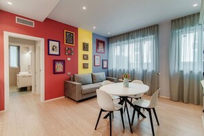 A modern living room with a sofa, dining table, chairs, and a kitchen area visible through an open door. - Home Three Colors - MyHomeinComo (Como)
