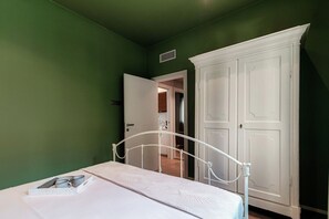 A bedroom with a single bed, a white metal headboard, a white wardrobe, and a green wall. - Home Three Colors - MyHomeinComo (Como)