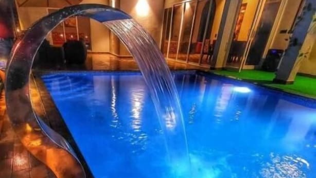 A swimming pool with a clear water feature and wooden deck. - Wandr Tryo Villa Karjat (Khalapur)