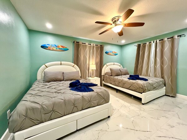 Quarto com duas camas, ventoinha no teto e piso de mármore.