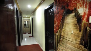 Un couloir avec un tapis rouge, une porte en bois et un mur dont la peinture s’écaillait.