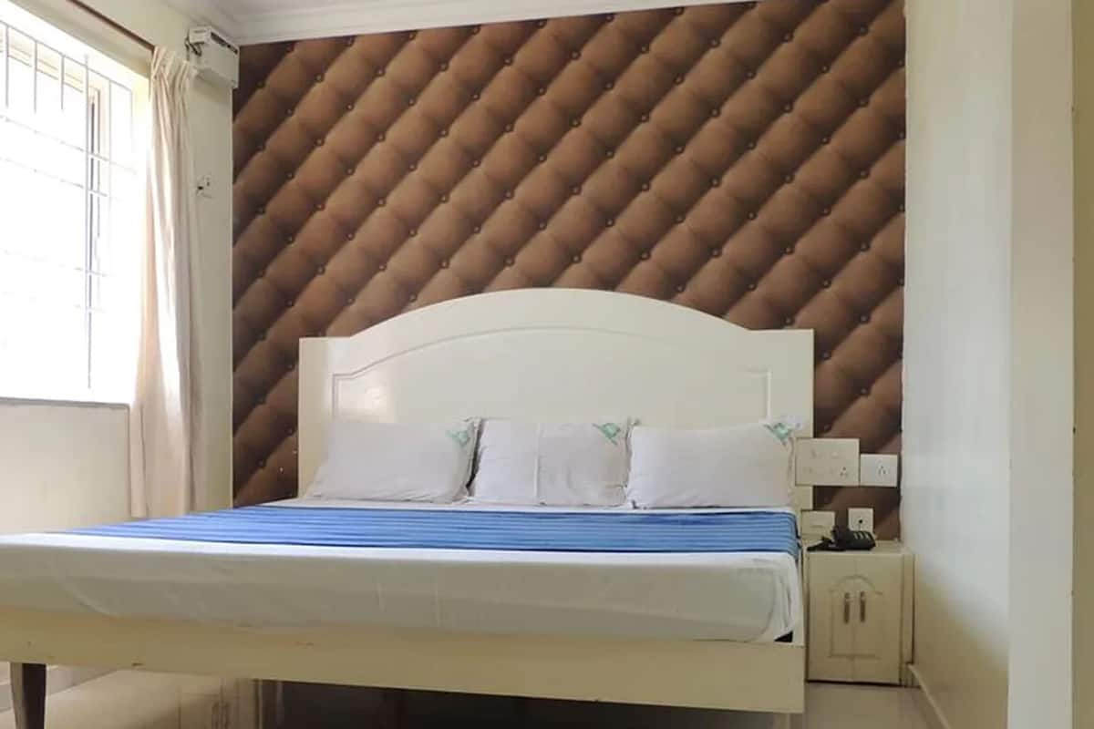 A bedroom with a bed, a nightstand, and a wall with a diamond-patterned design.