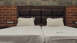 Un lit double avec une tête de lit sombre, deux oreillers et un couvre-lit blanc.