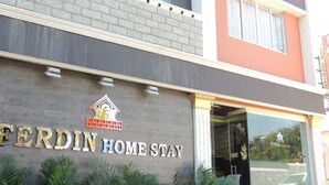 Un bâtiment sur lequel on peut lire l’inscription « FERDIN HOME STAY » et qui arbore un logo représentant une maison avec un toit rouge.