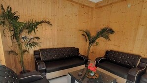 Una stanza con due divani in pelle nera, un tavolino da caffè in vetro con un centrotavola decorativo e pareti rivestite in legno.