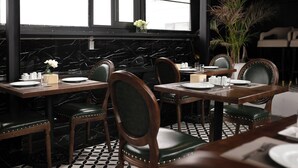 Ein Restaurant mit Marmorwänden, schwarz-weiß gefliestem Boden und Holztischen und -stühlen.