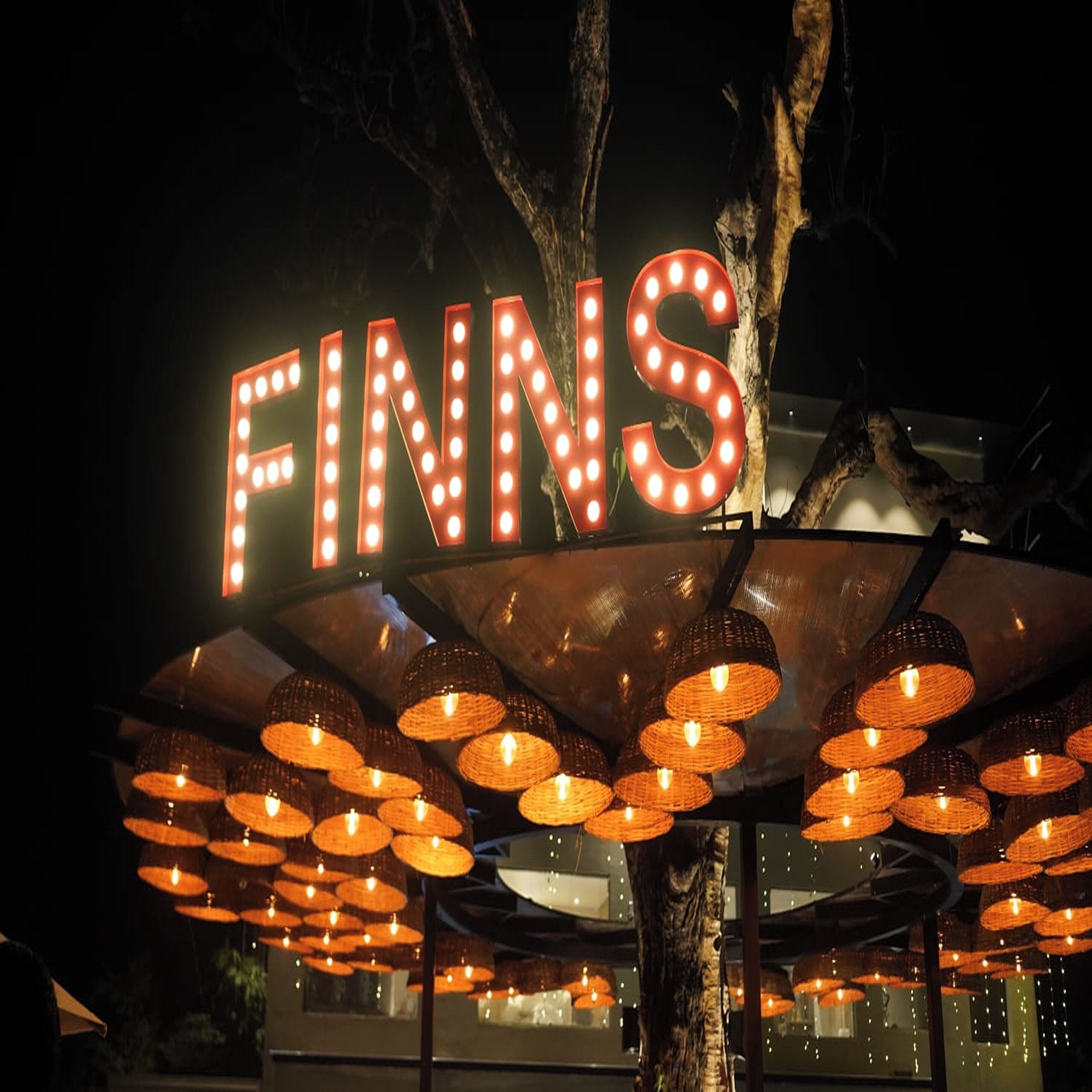 Un letrero grande iluminado con la palabra "FINNS" y un aplique decorativo debajo.