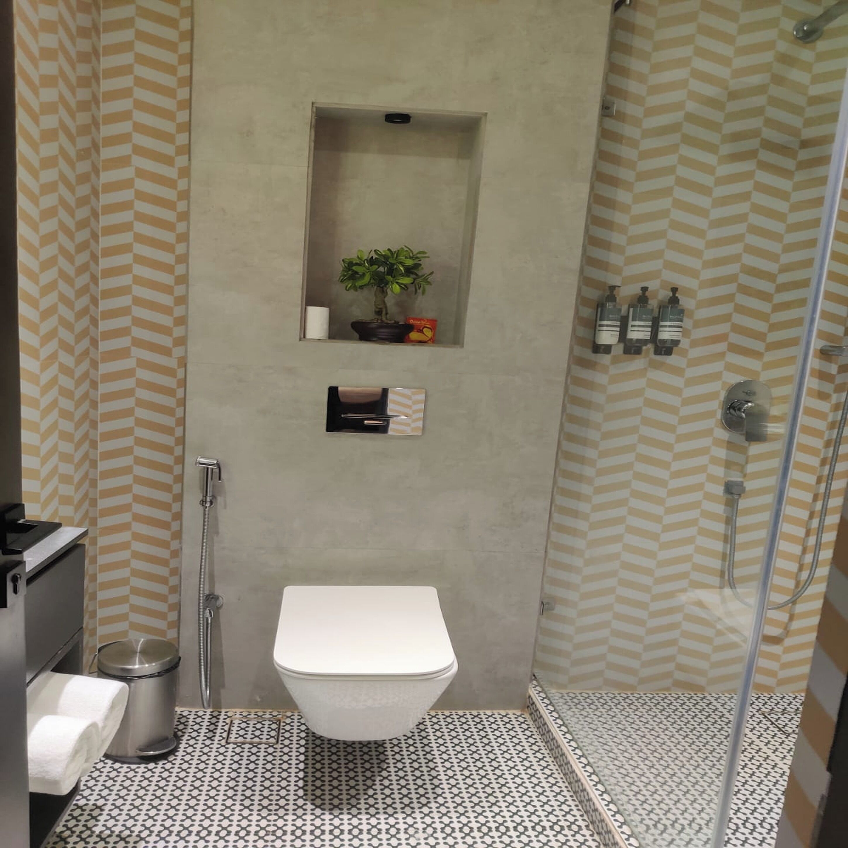 A bathroom with a toilet, a shower, a sink, and a small shelf with toiletries.