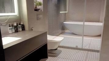 Un baño moderno con una bañera independiente grande, un tocador con espejo y una zona de ducha.