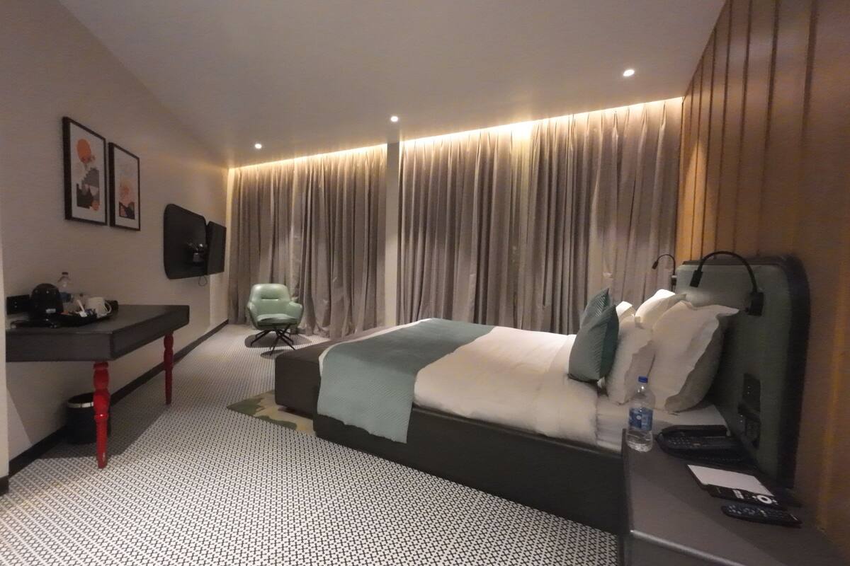 Habitación de hotel con cama, escritorio, silla y televisor.