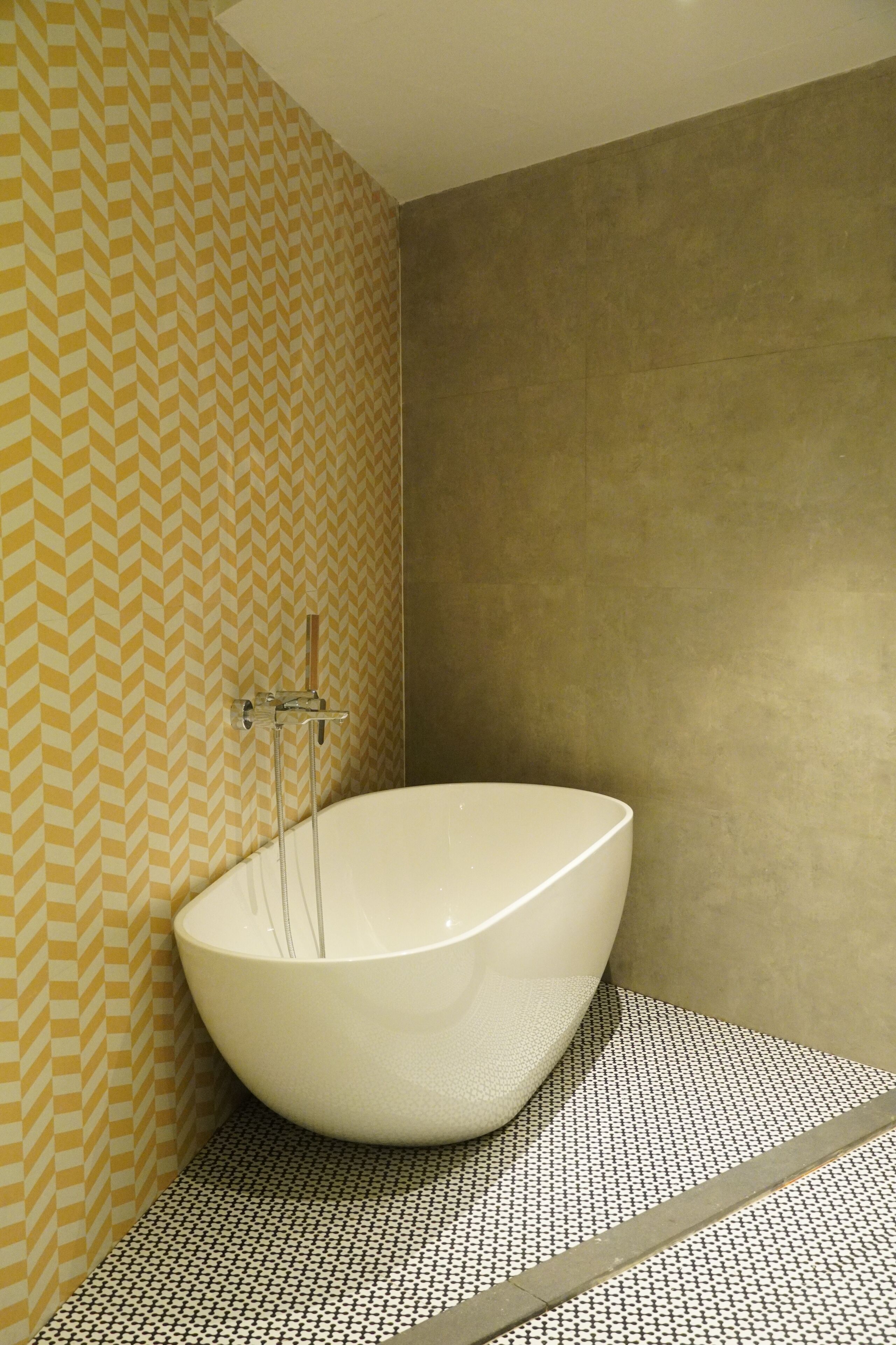 A modern bathroom with a freestanding bathtub, patterned wallpaper, and tiled flooring.