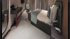 Ein modernes Hotelzimmer mit Bett, Schreibtisch, Stuhl und Fernseher.