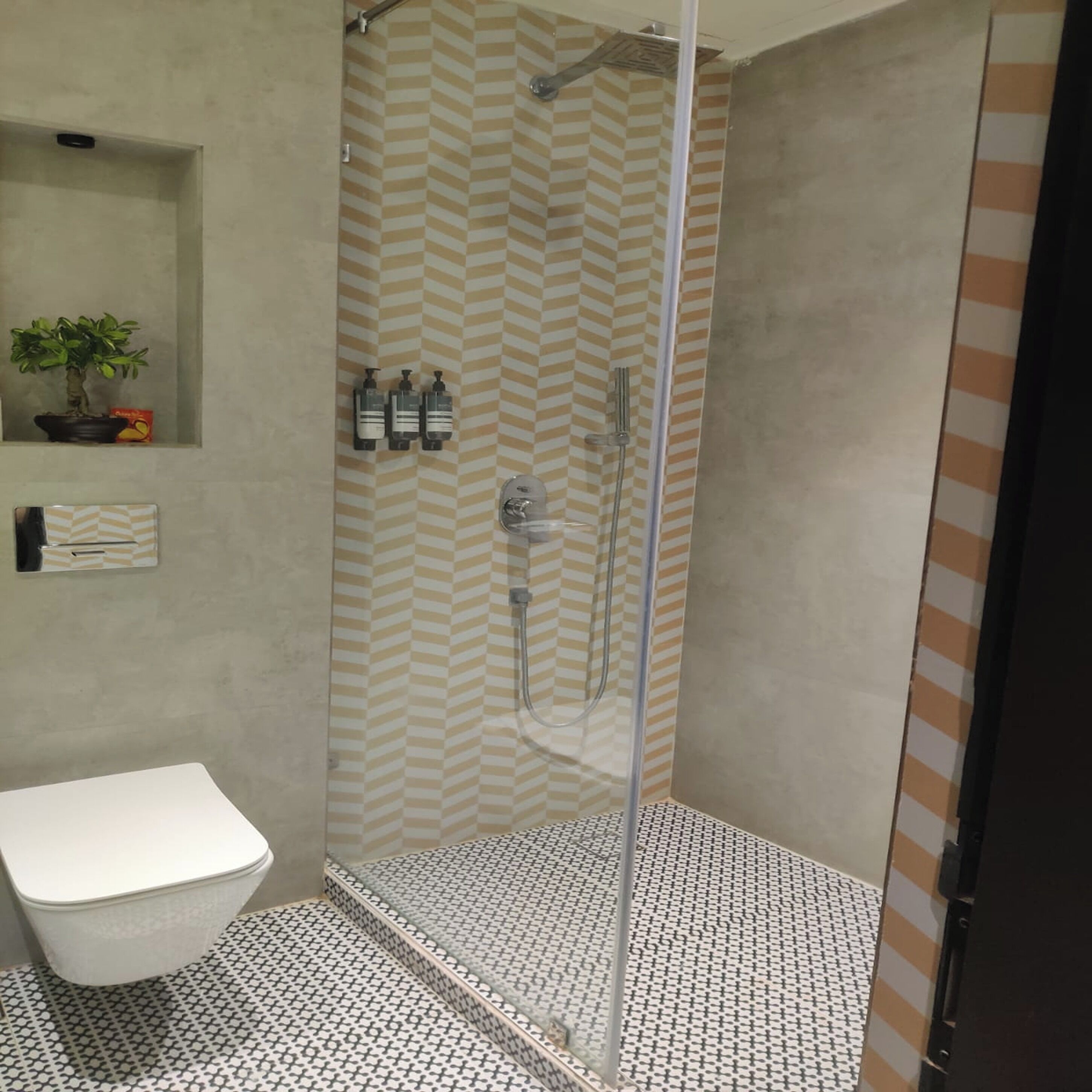 Ein modernes Badezimmer mit Dusche, Toilette und einem kleinen Ablagebereich für Toilettenartikel.