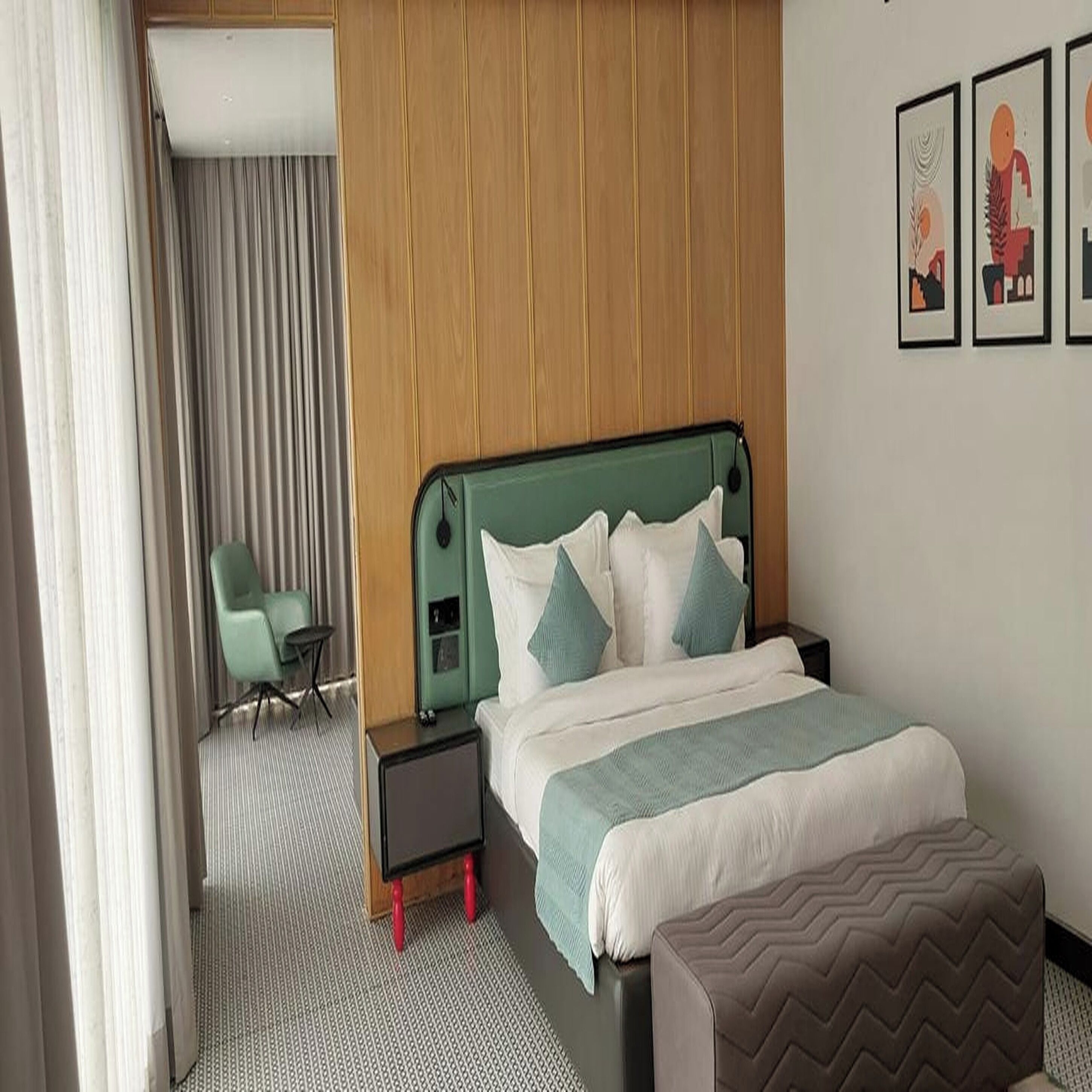 Une chambre d’hôtel avec un lit, une chaise, une table de chevet et un mur orné de tableaux.