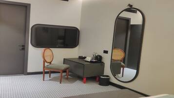 Una camera d'albergo moderna con un letto, una scrivania, una sedia, un grande specchio e una televisione a parete.