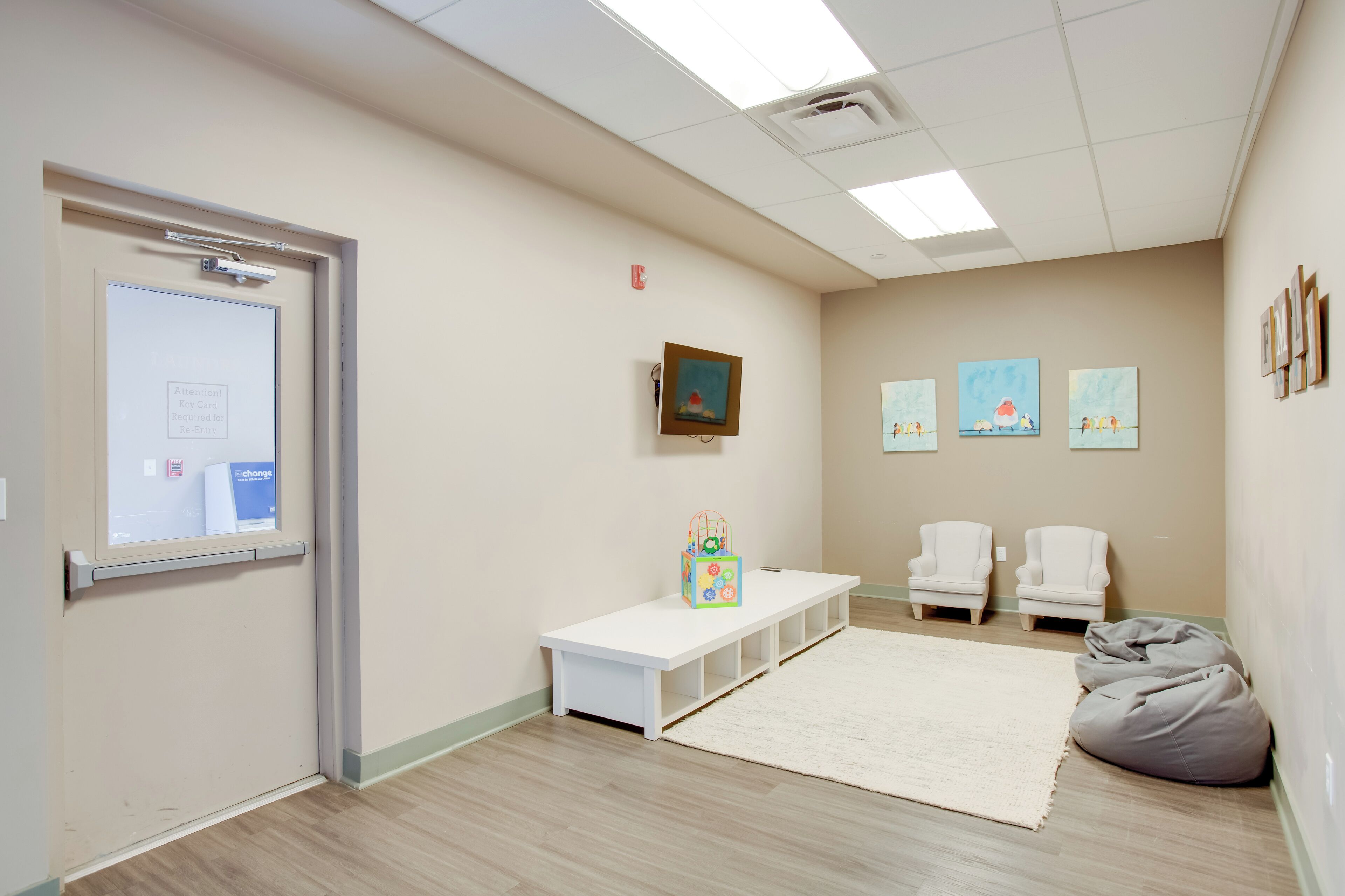 A room with a white bench, a white carpet, and two white chairs.