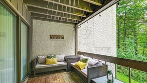 A wooden deck with wicker furniture and a sign that says "EXPLORE". - Sapphire Valley Condo w/ Pool & Lake Beach Access! (Sapphire)