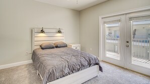 Ein Schlafzimmer mit Bett, Nachttischen, Deckenventilator und einer Tür mit Blick ins Freie.