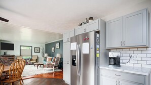 A modern kitchen with a built-in refrigerator, a coffee maker, and a dining area with a wooden table and chairs.