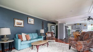 A living room with a blue sofa, patterned armchairs, a coffee table, and a white shag rug.