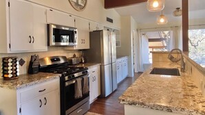 A modern kitchen with white cabinets, stainless steel appliances, granite countertops, and pendant lighting. - Spa, 5 minutes from Sequoia National Park. Spacious, convenient and private. (Three Rivers)