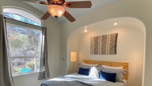 A bedroom with a bed, a ceiling fan, a window with curtains, and a wall-mounted artwork. - Spa, 5 minutes from Sequoia National Park. Spacious, convenient and private. (Three Rivers)