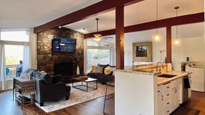 A spacious living area with a stone fireplace, a sofa, and a coffee table. There is a kitchen area with a sink and a countertop. - Spa, 5 minutes from Sequoia National Park. Spacious, convenient and private. (Three Rivers)