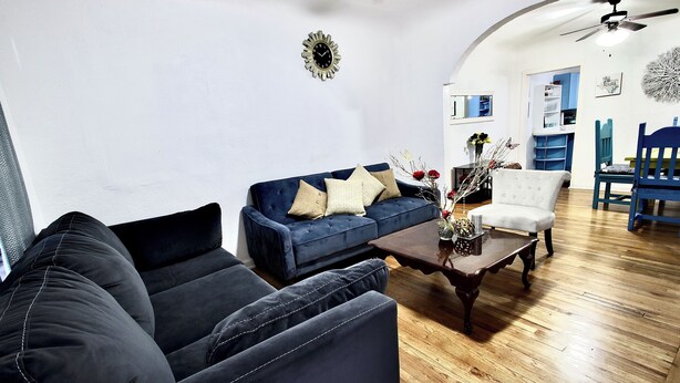 Una sala de estar con un sofá azul, un sillón blanco y una mesa de centro de madera.