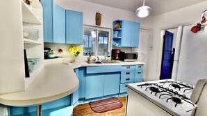 Una cocina con armarios azules, encimera blanca, estufa a gas y microondas.