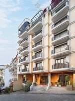 Un hotel de varios pisos con balcones, una entrada de alfombra roja y un exterior bien cuidado.