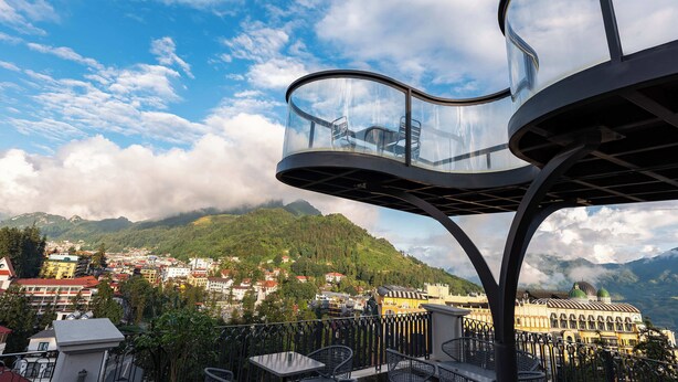 Un balcón con cerramiento de vidrio que da a una vista de un pueblo y montañas.