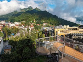 A hotel with a modern design, featuring a curved balcony with outdoor seating.