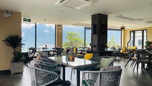 Un restaurante con techo alto, amplias ventanas y vistas a montañas.