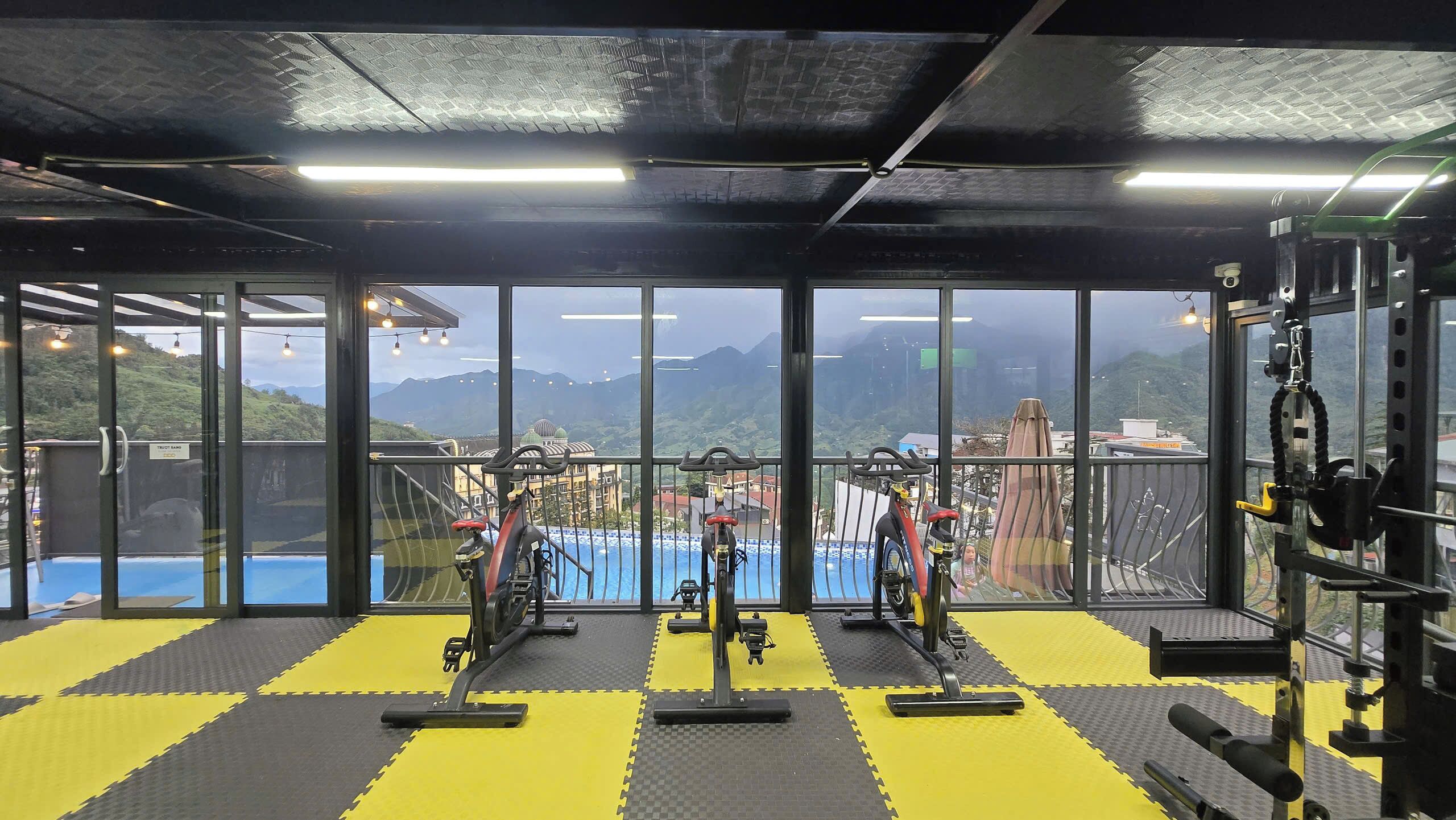 A gym with exercise equipment, large windows, and a view of mountains.