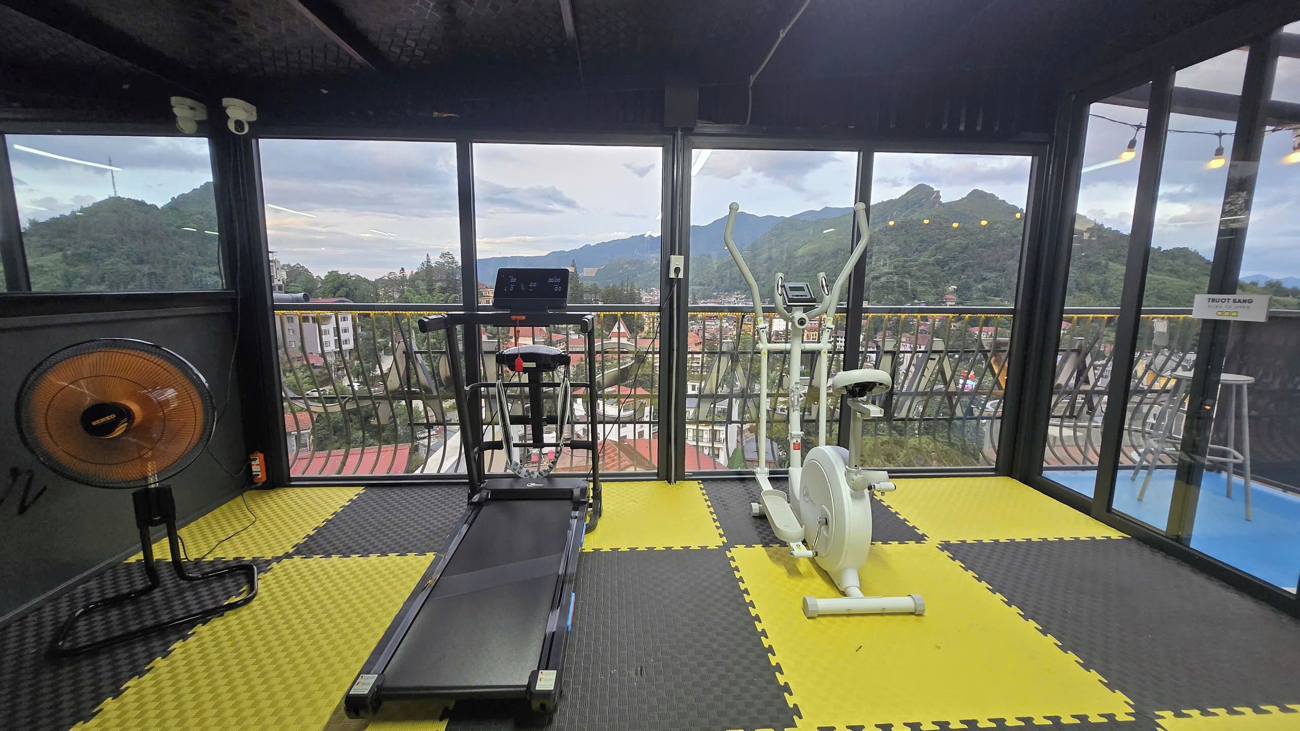 A gym with exercise equipment, a treadmill, and a fan.