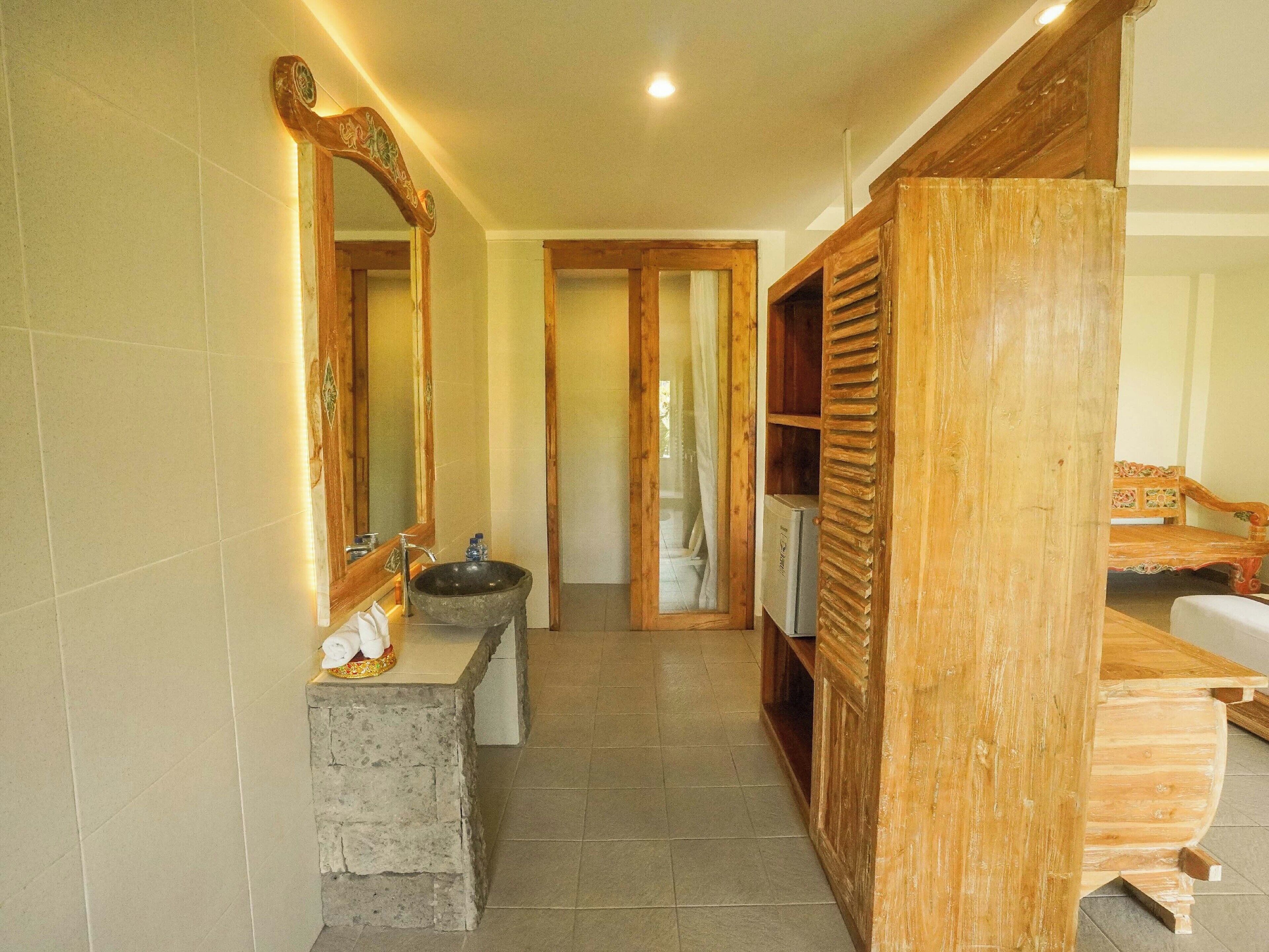A bathroom with a stone sink, wooden vanity, and a mirror with a decorative frame.