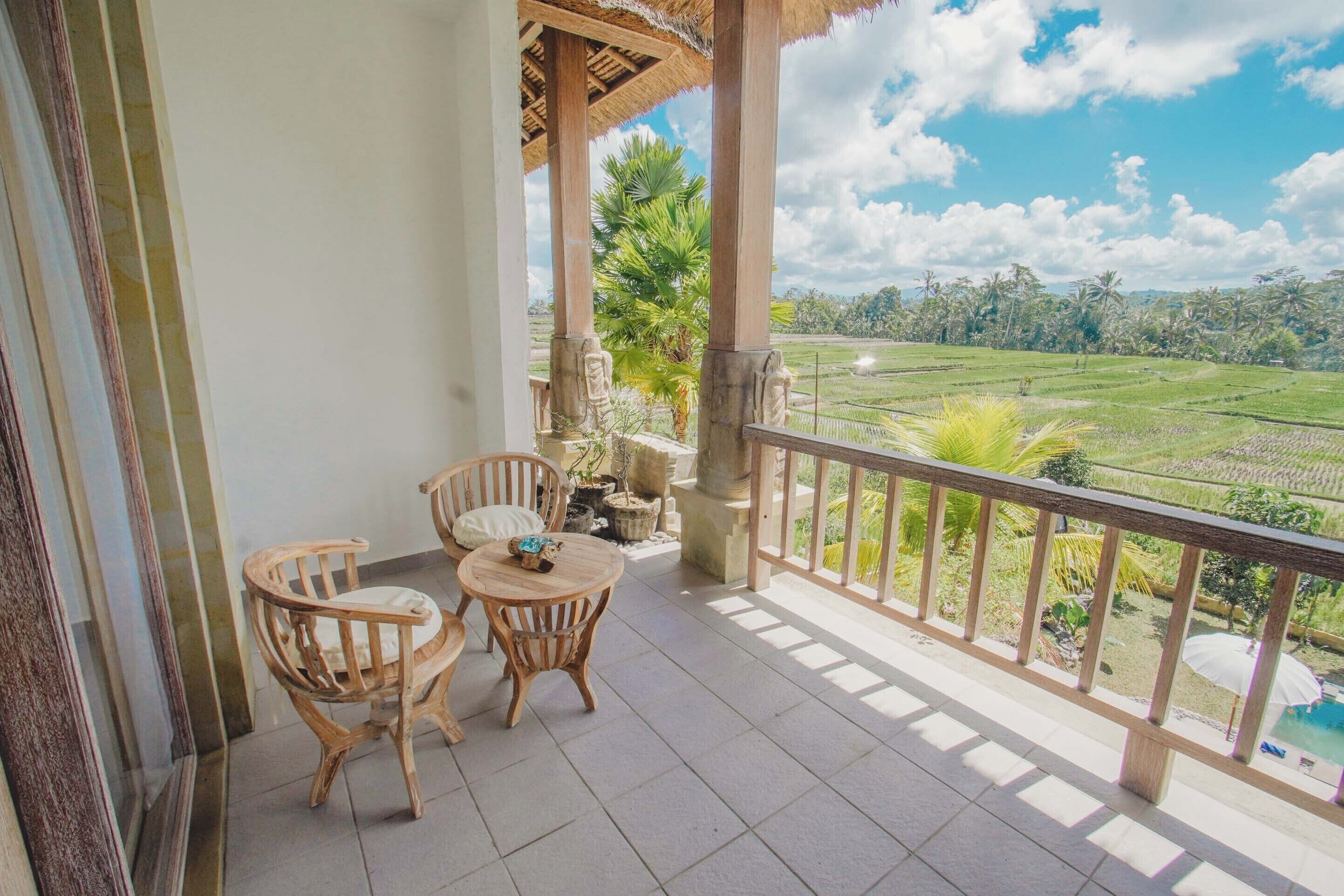 A balcony with a view of a green field and palm trees.