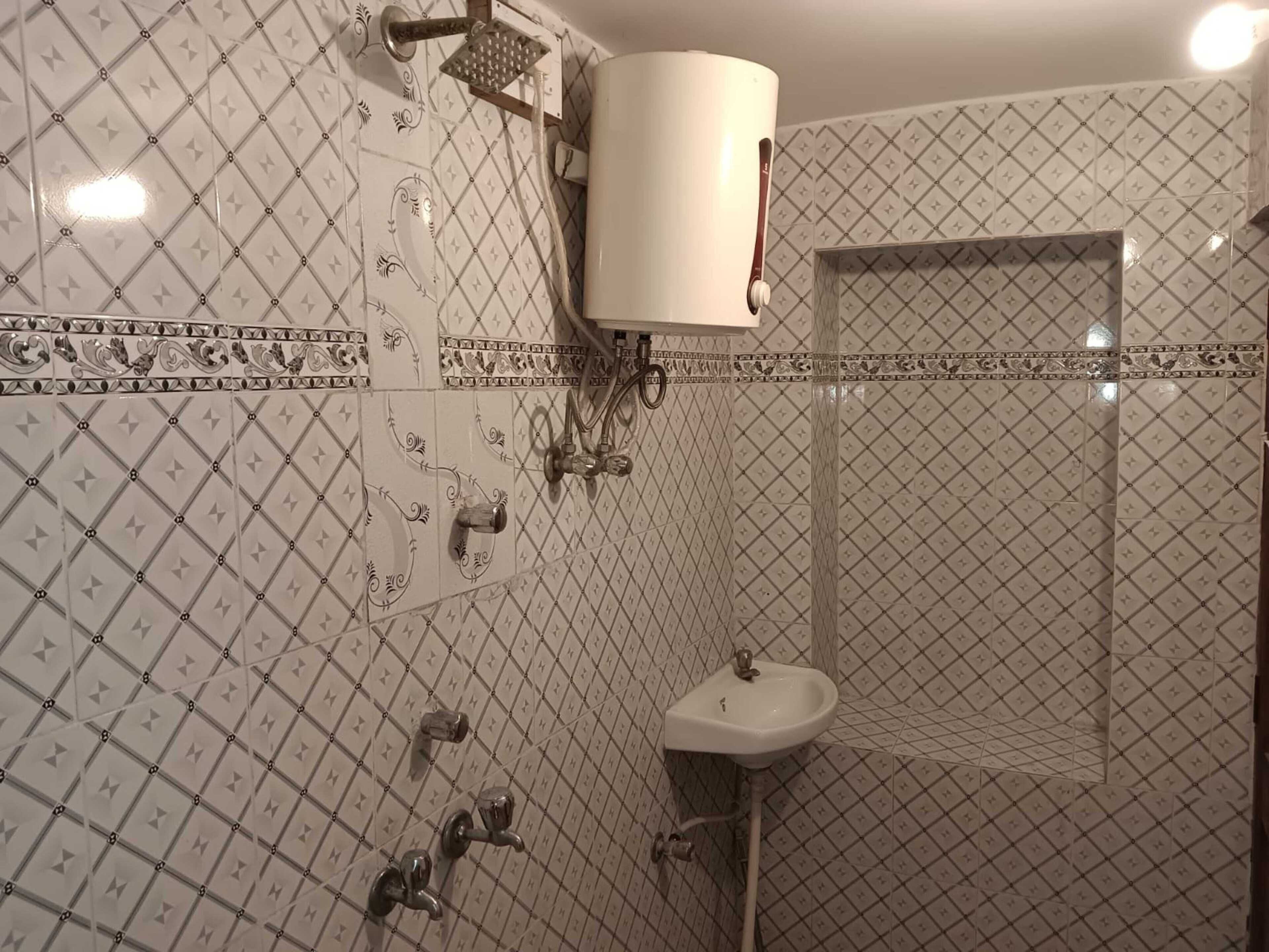 Casa de banho com azulejos estampados, uma pia e um chuveiro.