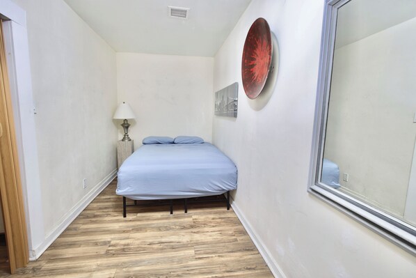 A bedroom with a bed, a lamp, a picture on the wall, and a window.
