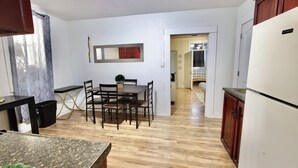 Una cocina con armarios de madera, una mesa de comedor con sillas y un refrigerador.