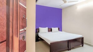 A bedroom with a bed, a nightstand, a ceiling fan, and a wooden wardrobe. - iROOMZ Eco Avasya Residency (Hyderabad)
