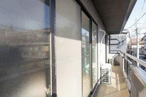 A balcony with a metal railing, a glass door, and a small white chair. - TOYOTSUKI (Osaka)