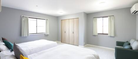 Una habitación de hotel moderna con dos camas, un sofá verde y un armario.