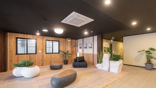 Un interior moderno con paredes de madera, techo negro y un mostrador de recepción con plantas.