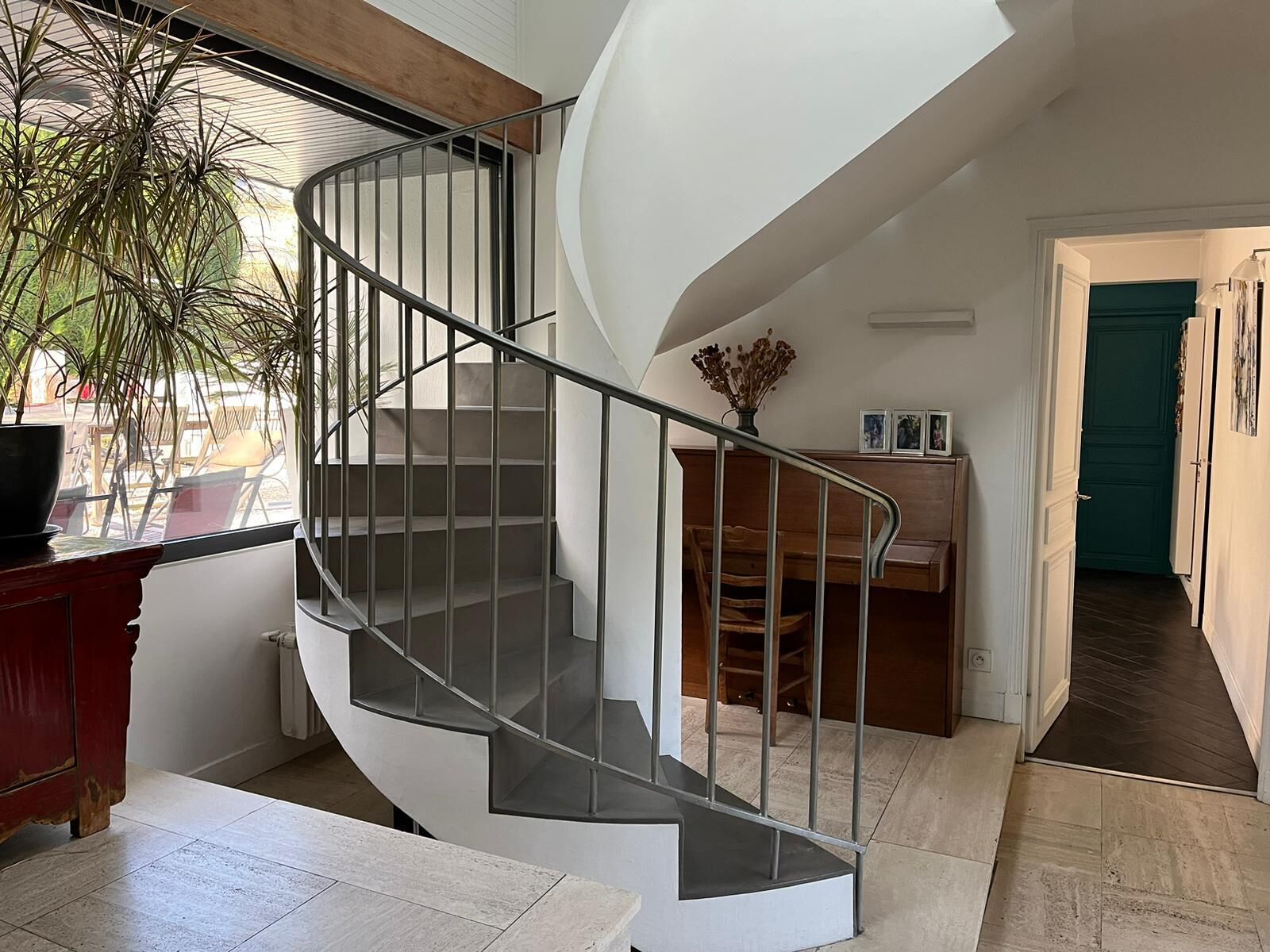 A modern interior with a spiral staircase, a wooden bench, and a view of the outdoors.