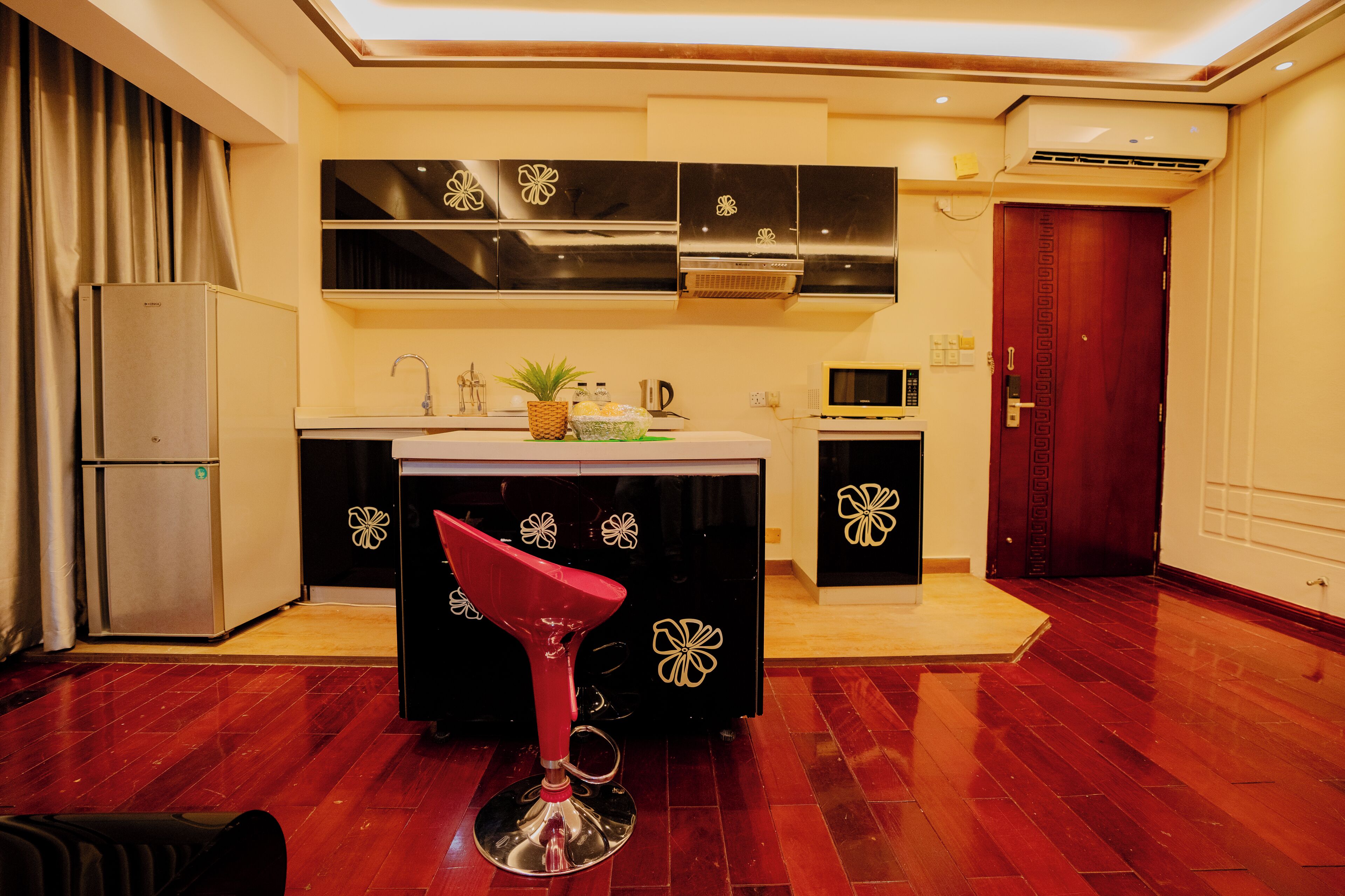 A modern kitchen with a central island, stainless steel appliances, and a red bar stool.