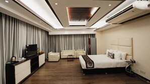 A modern hotel room with a large bed, a sofa, a TV, and a desk. - Royal Residence Dhaka (Dhaka)