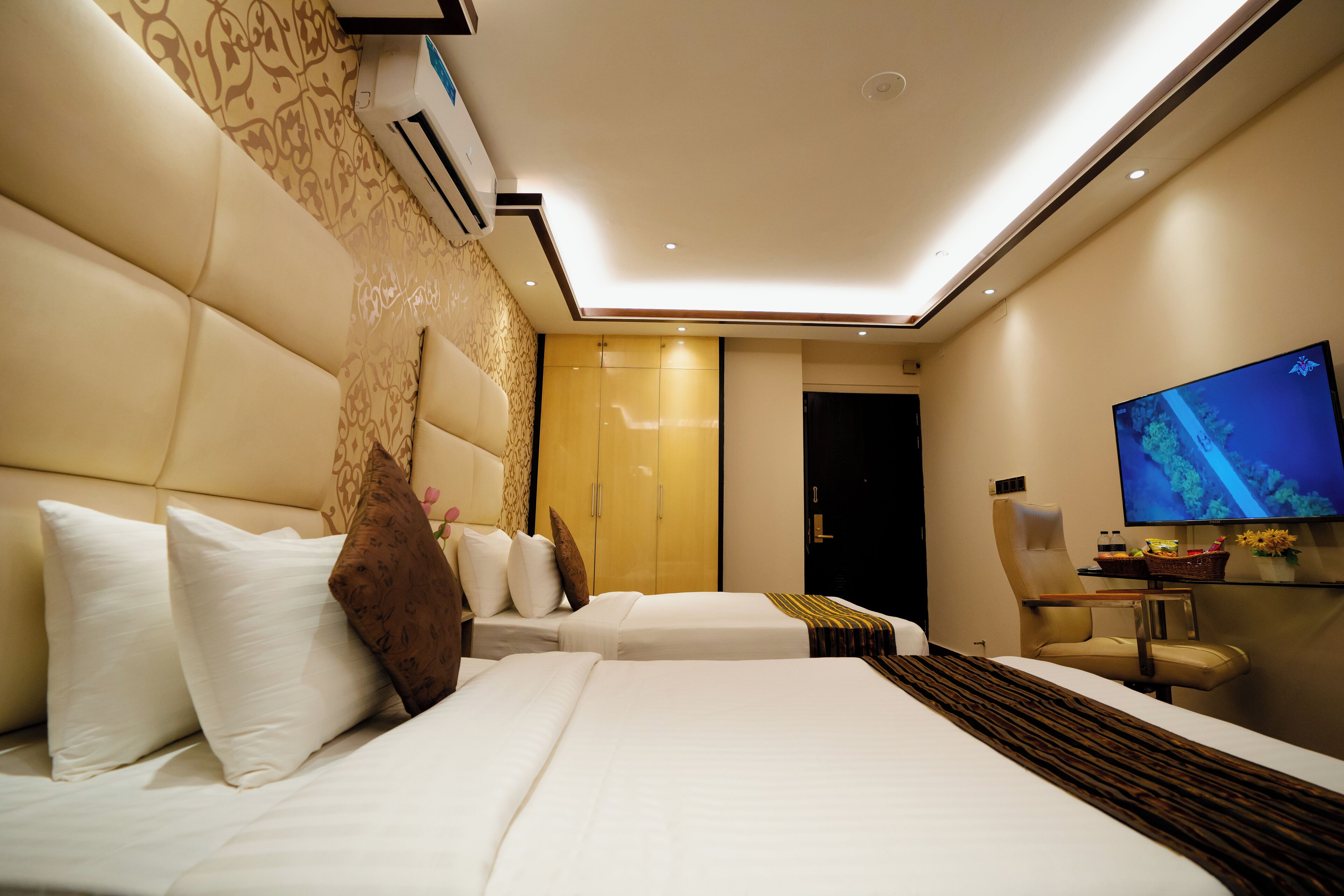 A hotel room with two beds, a television, a desk, and a wardrobe.