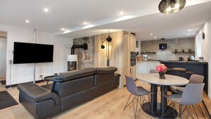 Un espacio habitable moderno con sofá, mesa de comedor, sillas, televisor de pantalla plana y zona de cocina.