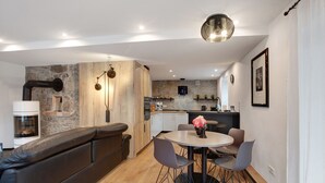 Una cocina moderna con pared de piedra, armarios de madera y horno empotrado.
